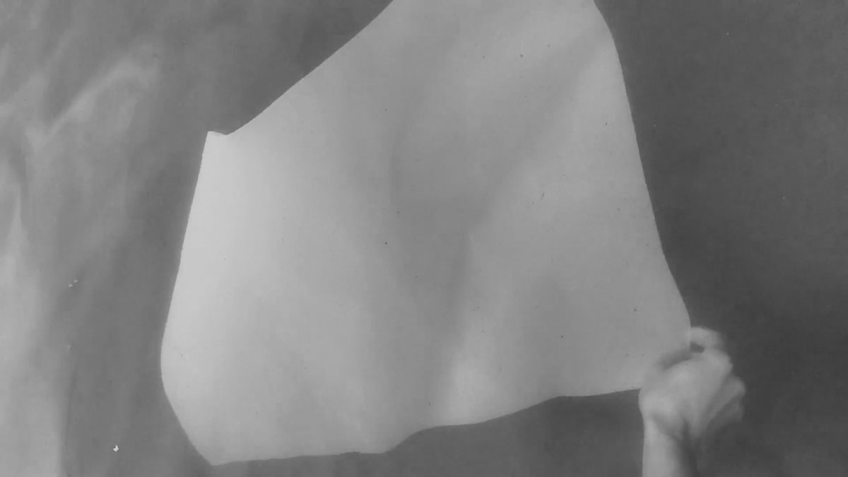 A hand pulling the bottom right corner of a sheet of paper underwater